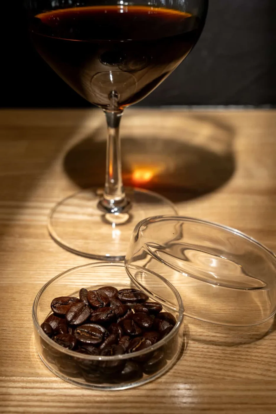 木のカウンターに置かれたワイングラスの一杯と豆