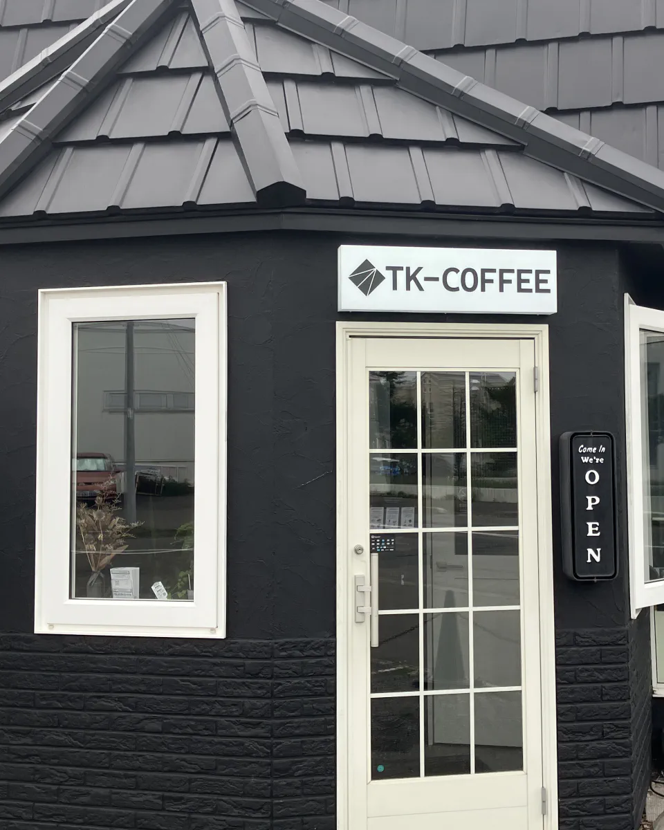 黒い外壁と白い入口が印象的なTK-COFFEEの外観